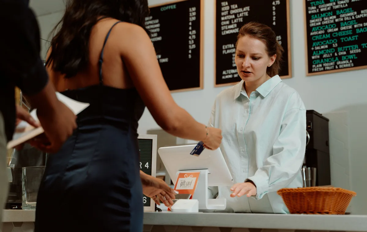 Emprendedora atendiendo un pago con tarjeta en cafetería
